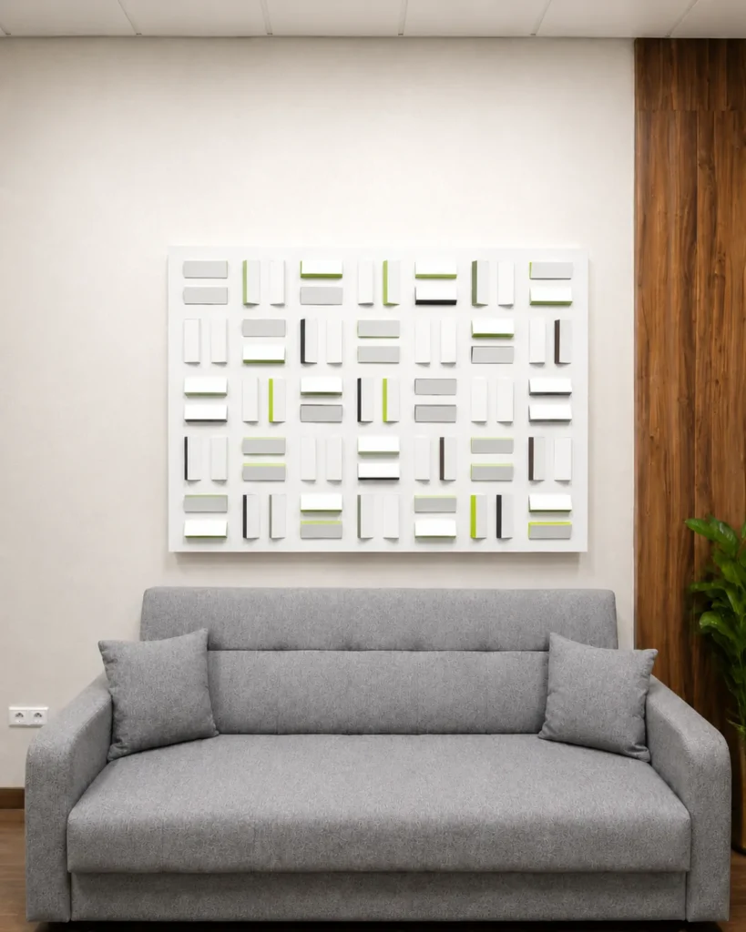 Relief géométrique blanc et vert installé au-dessus d’un canapé gris